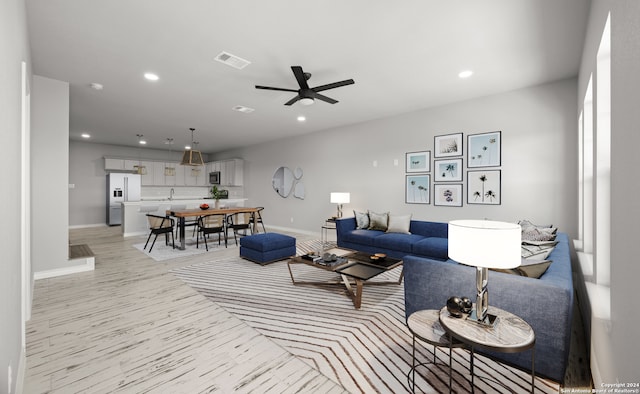 living room featuring sink, light hardwood / wood-style flooring, and ceiling fan