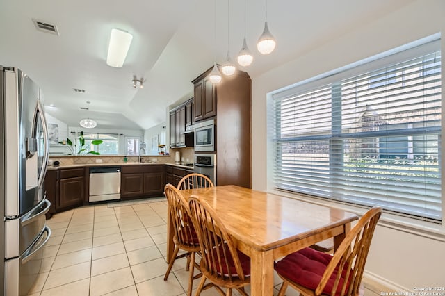 kitchen with vaulted ceiling, dark brown cabinetry, stainless steel appliances, and light tile patterned floors