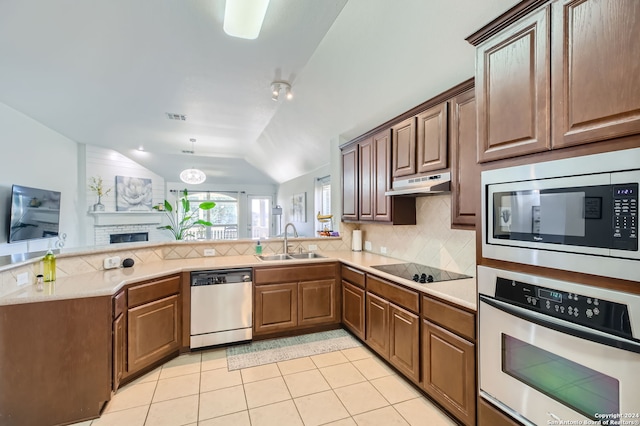 kitchen with sink, a brick fireplace, stainless steel appliances, lofted ceiling, and light tile patterned floors