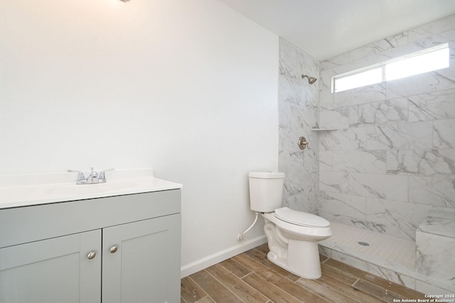 bathroom featuring vanity, toilet, hardwood / wood-style flooring, and tiled shower