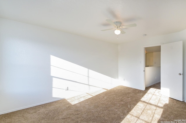 spare room with ceiling fan and light colored carpet