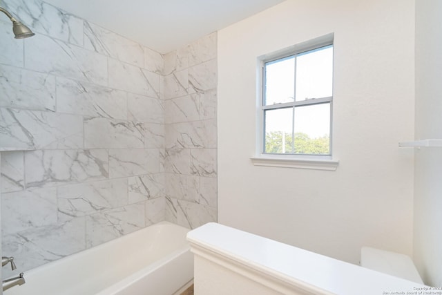 bathroom featuring tiled shower / bath combo and toilet