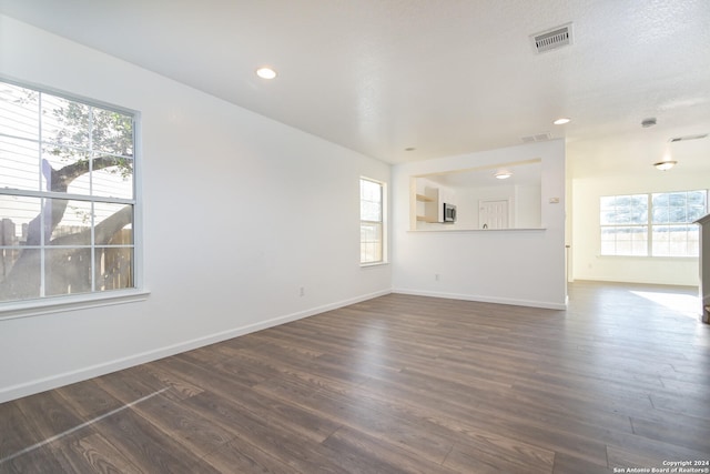 spare room with dark hardwood / wood-style floors, a healthy amount of sunlight, and a textured ceiling