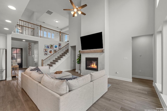 living room featuring hardwood / wood-style floors, a wealth of natural light, a high ceiling, and ceiling fan