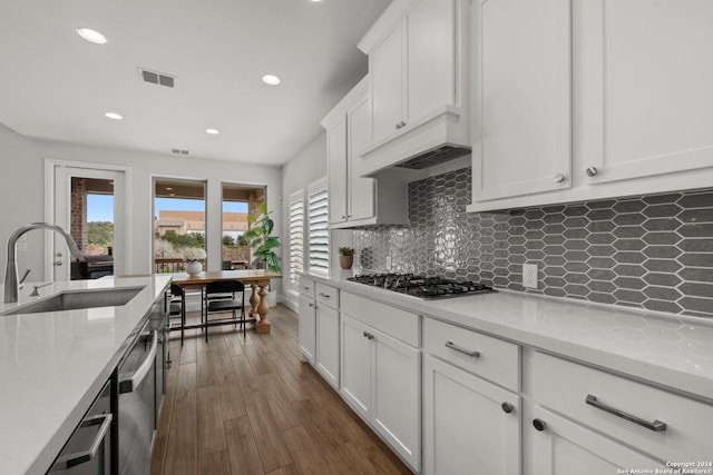 kitchen with dark hardwood / wood-style floors, stainless steel appliances, sink, light stone countertops, and white cabinets