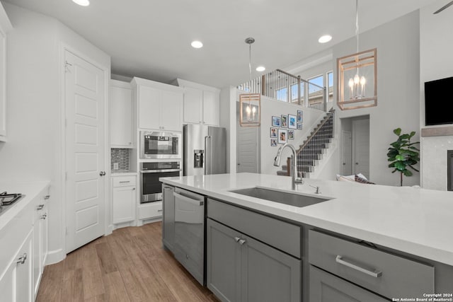 kitchen featuring white cabinets, appliances with stainless steel finishes, sink, pendant lighting, and gray cabinets