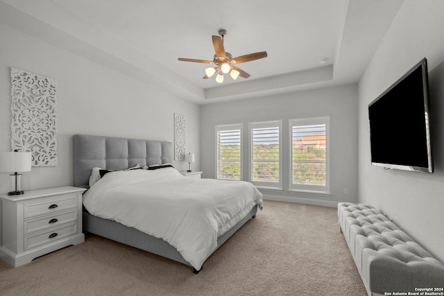 carpeted bedroom with radiator, a tray ceiling, and ceiling fan