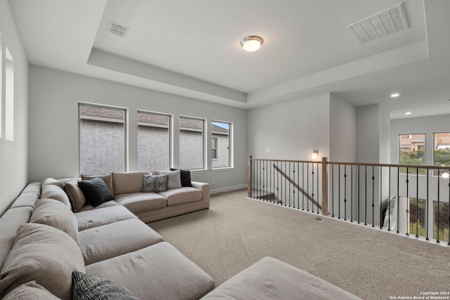 living room featuring light carpet and a tray ceiling