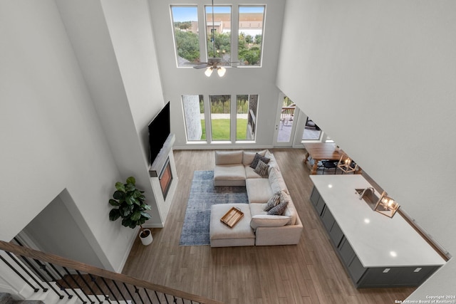 living room featuring light hardwood / wood-style floors, a high ceiling, and ceiling fan