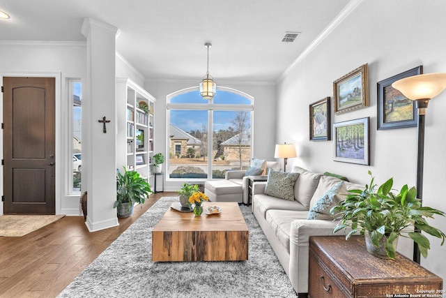 living room featuring dark wood-type flooring, crown molding, and decorative columns