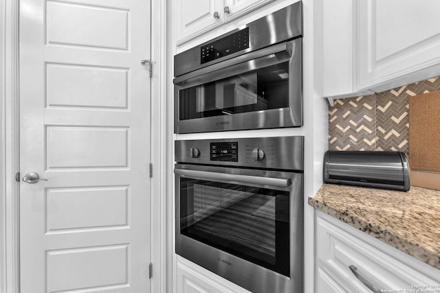 kitchen with white cabinetry, double oven, decorative backsplash, and light stone countertops