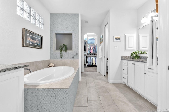 bathroom featuring vanity, tile patterned flooring, and tiled bath