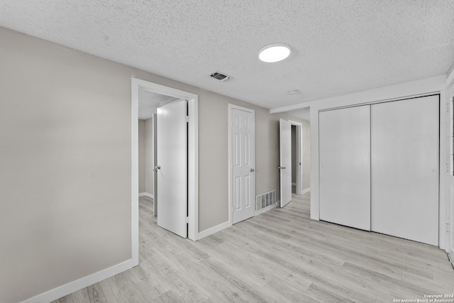 unfurnished bedroom with a closet, a textured ceiling, and light wood-type flooring