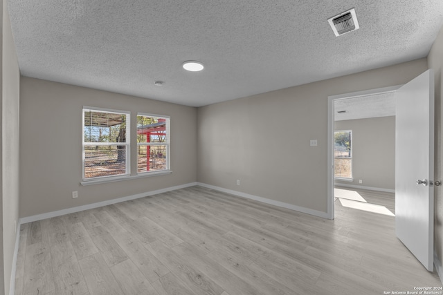 unfurnished room featuring a textured ceiling and light wood-type flooring