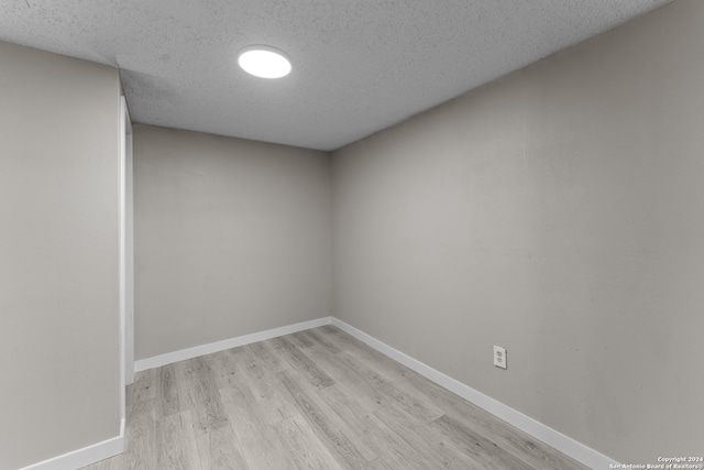 unfurnished room with a textured ceiling and light wood-type flooring