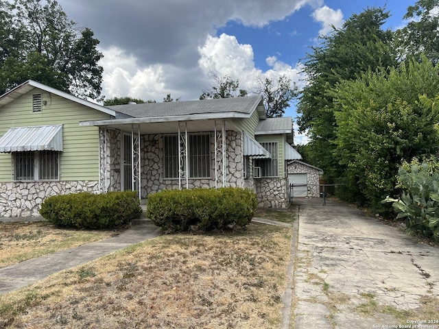 627 Canton, San Antonio, TX 78202 - bungalow-style house with stone siding, a porch, an outbuilding, a shingled roof, and a gate