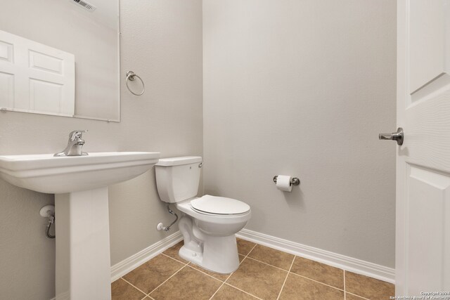 bathroom with toilet, sink, and tile patterned flooring