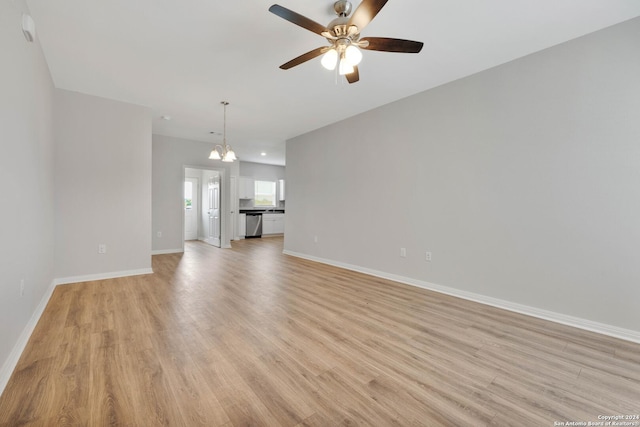 518 Precious Dr, San Antonio, TX 78237 - unfurnished living room with baseboards, ceiling fan with notable chandelier, and light wood-style flooring