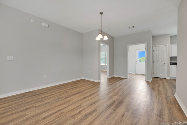 spare room with a chandelier and light hardwood / wood-style flooring