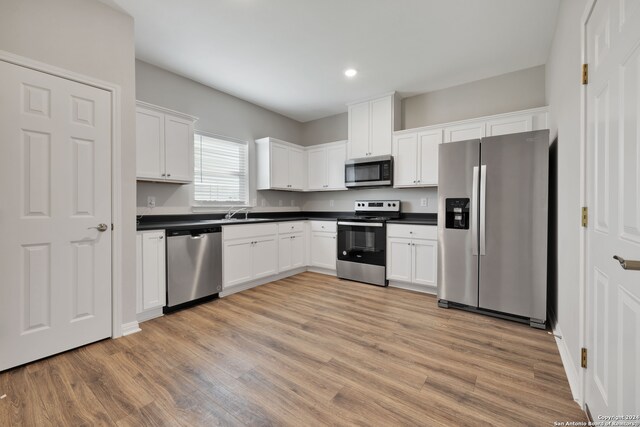 kitchen with white cabinetry, light hardwood / wood-style floors, appliances with stainless steel finishes, and sink