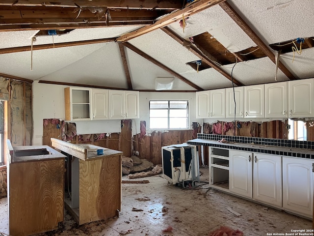 kitchen featuring white cabinetry and vaulted ceiling