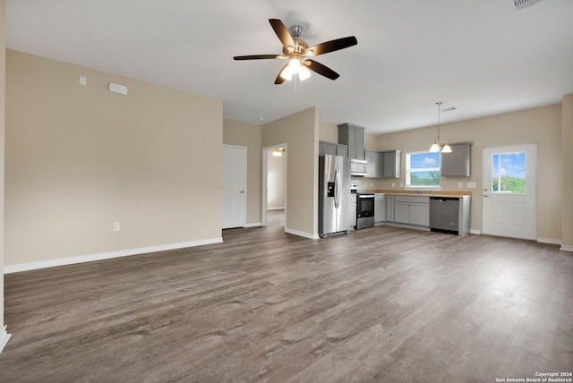 unfurnished living room featuring wood finished floors, baseboards, and a ceiling fan
