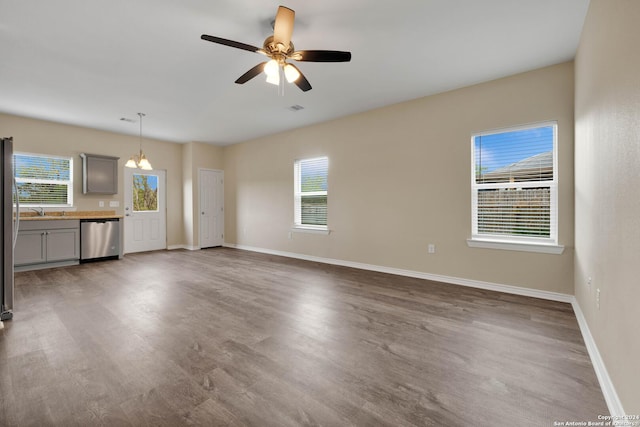 unfurnished living room featuring baseboards, ceiling fan, a sink, and wood finished floors