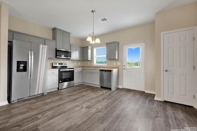 kitchen with stainless steel appliances, dark wood-type flooring, gray cabinetry, and visible vents