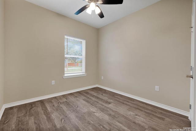 empty room with dark wood-type flooring, baseboards, and ceiling fan
