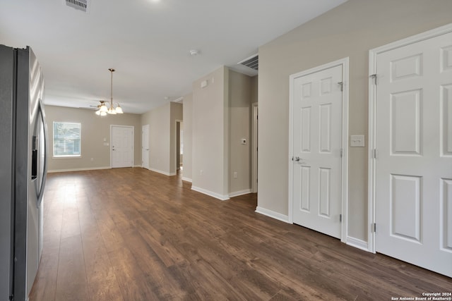 unfurnished living room featuring an inviting chandelier and dark hardwood / wood-style floors