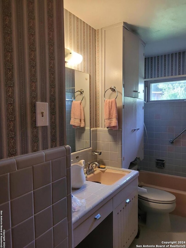 full bathroom with vanity, toilet, tile walls, and tiled shower / bath