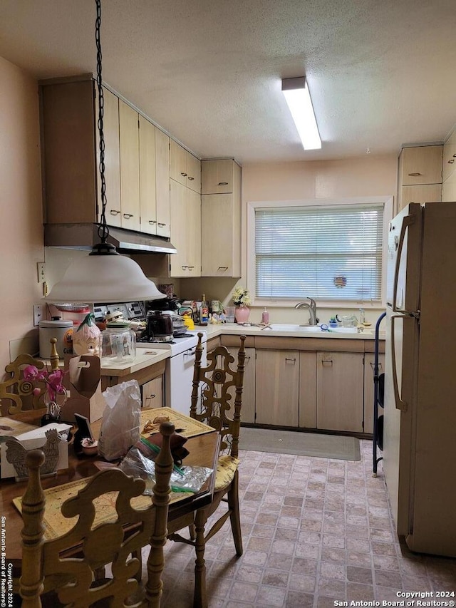 kitchen featuring a textured ceiling, cream cabinets, sink, and white appliances