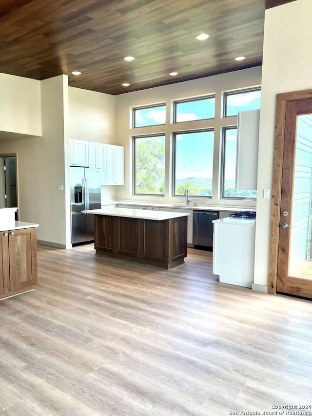 kitchen with a kitchen island, appliances with stainless steel finishes, wooden ceiling, light wood-type flooring, and sink