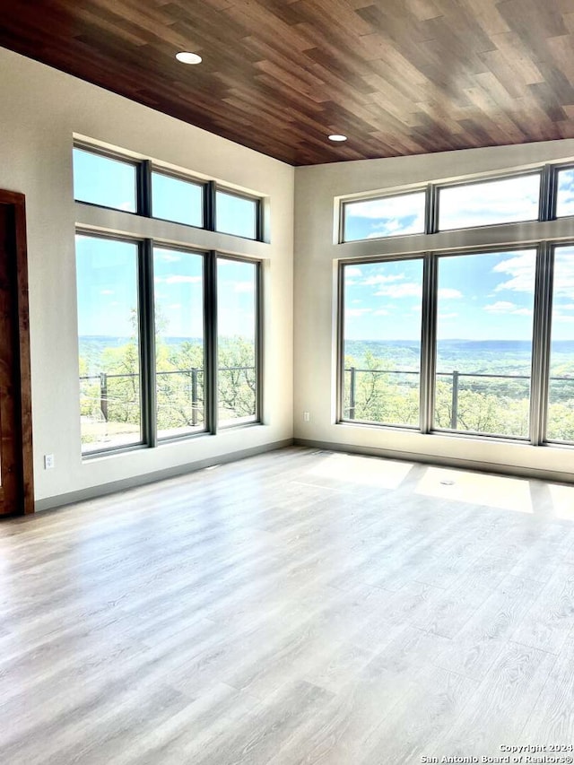 unfurnished room featuring wooden ceiling, a wealth of natural light, and light wood-type flooring