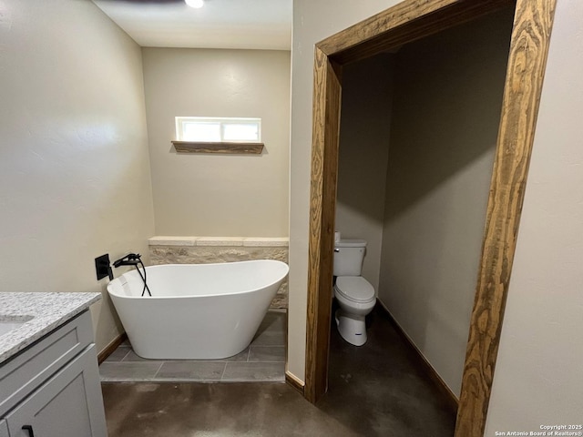 full bathroom featuring vanity, a freestanding tub, and toilet