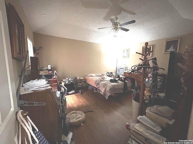 bedroom with ceiling fan, hardwood / wood-style flooring, and a textured ceiling