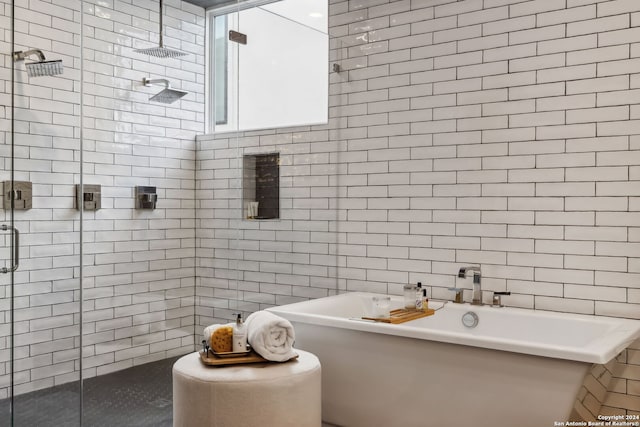 bathroom with tile walls and shower with separate bathtub