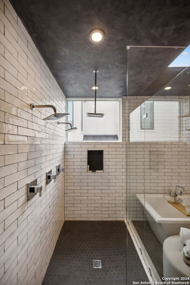 bathroom featuring a tile shower, tile walls, and a skylight