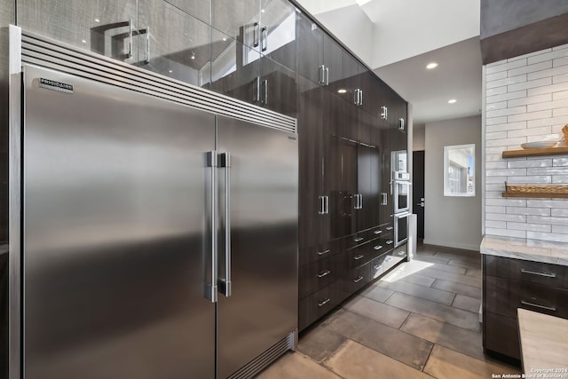 kitchen featuring appliances with stainless steel finishes, dark brown cabinets, and backsplash