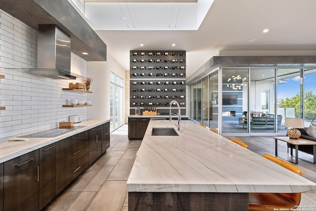 kitchen with black electric stovetop, tasteful backsplash, sink, a spacious island, and wall chimney exhaust hood