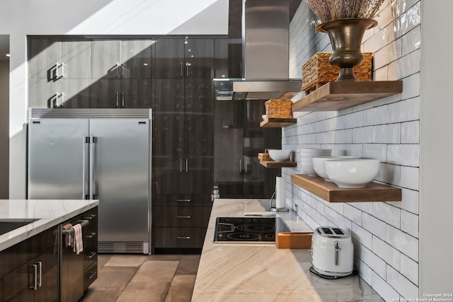 kitchen with wall chimney range hood, light stone countertops, stainless steel appliances, and backsplash