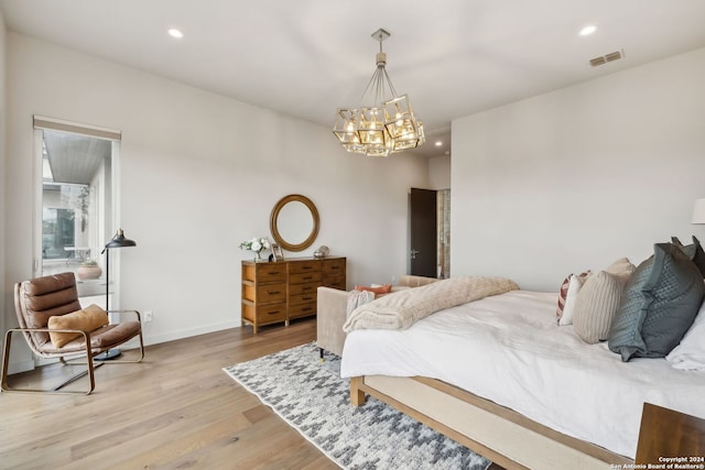 bedroom with light hardwood / wood-style floors and a notable chandelier