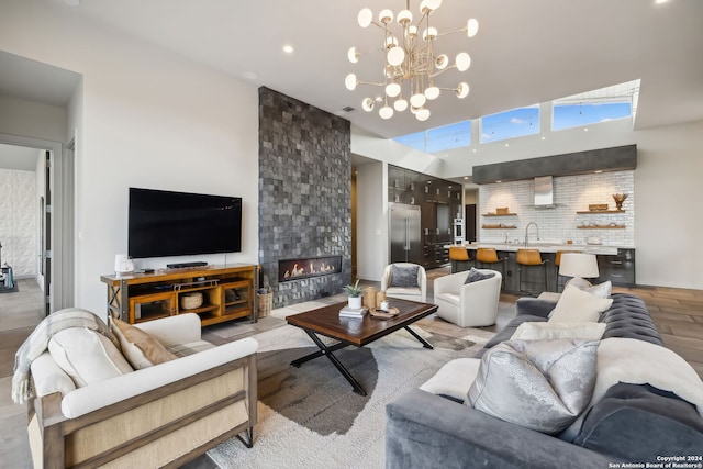 living room featuring a notable chandelier, a high ceiling, light wood-type flooring, and a fireplace