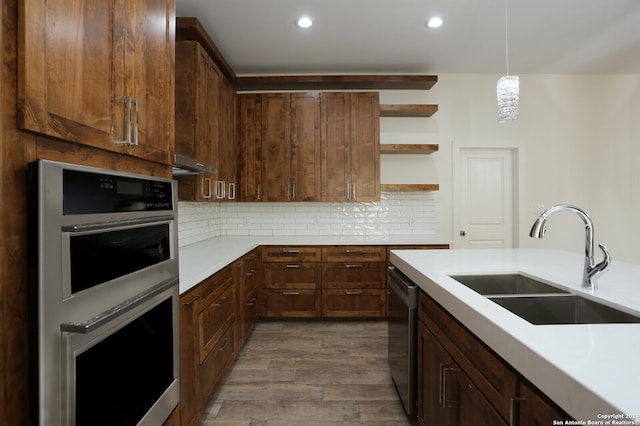 kitchen featuring tasteful backsplash, appliances with stainless steel finishes, sink, hardwood / wood-style floors, and pendant lighting