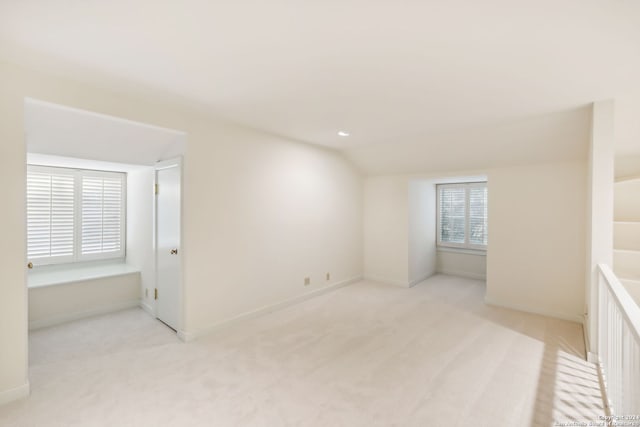 empty room with light carpet and vaulted ceiling