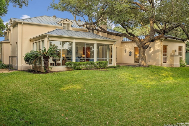 rear view of property with a sunroom and a yard