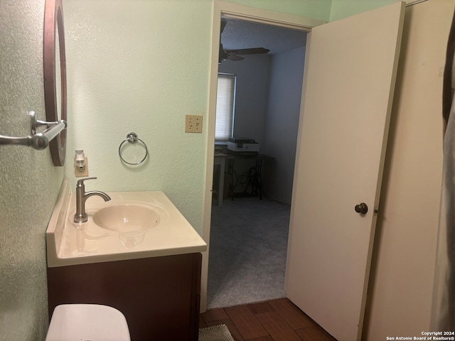 bathroom with vanity, hardwood / wood-style floors, ceiling fan, and a textured ceiling