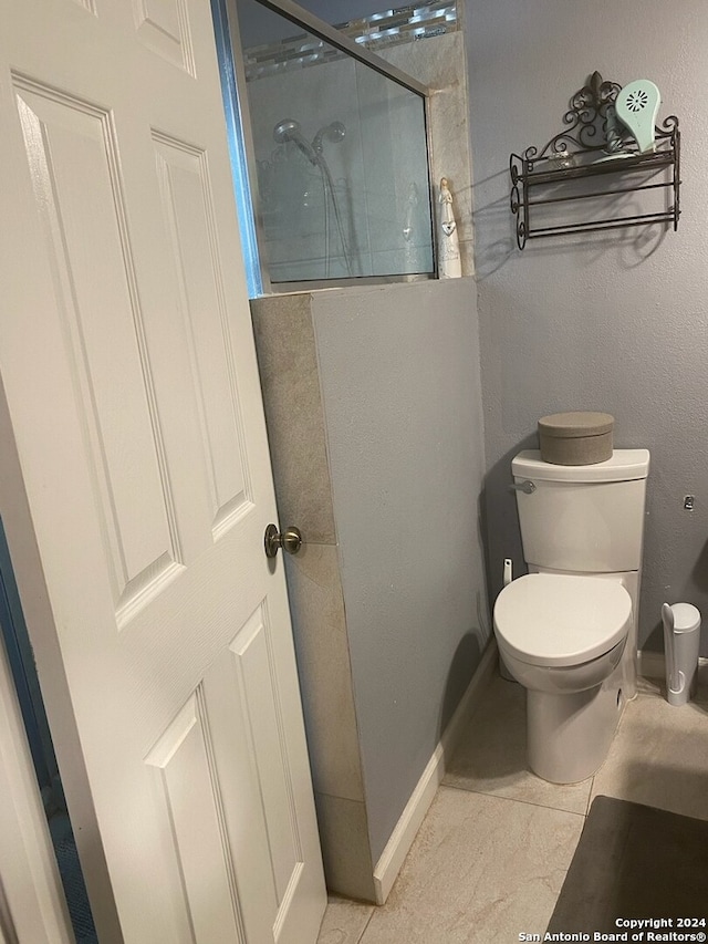 bathroom with toilet, tile patterned floors, and a shower with door