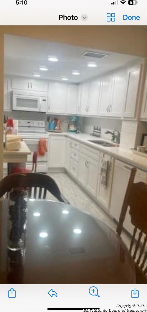 kitchen featuring white cabinetry, sink, and white appliances