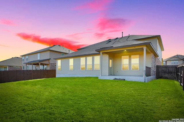 back house at dusk with a lawn